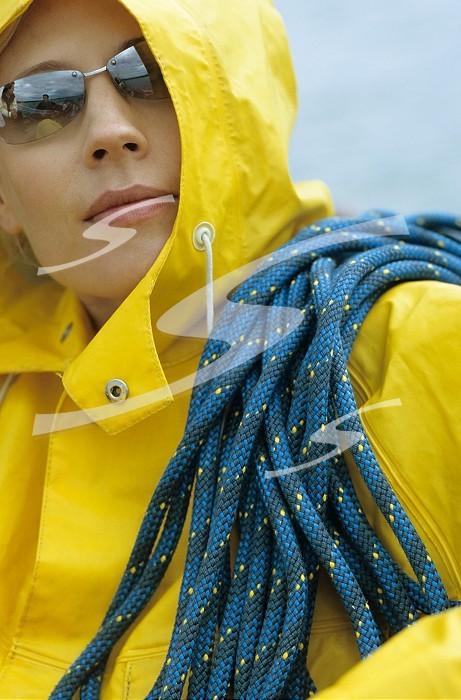 Woman in yellow raincoat and sunglasses with rope over her shoulder