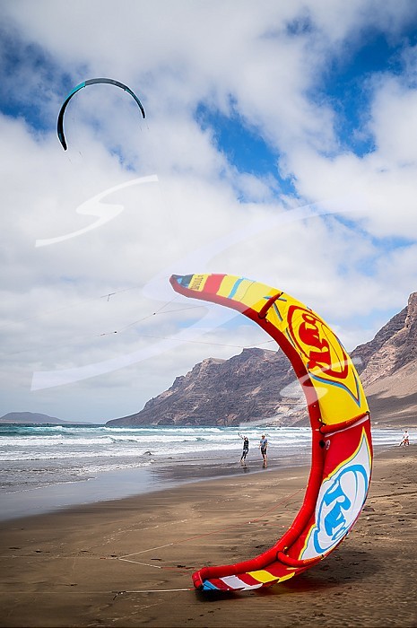 Kite surfers in Famara beach (Playa de Famara), 6km golden sand beach located within the Natural Park of the Chinijo Archipelago, between the fishing village of La Caleta de Famara and the base of the impressive cliffs of Famara, Lanzarote, Canary Islands, Spain