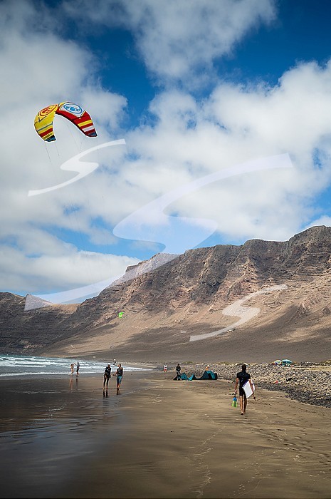 Kite surfers in Famara beach (Playa de Famara), 6km golden sand beach located within the Natural Park of the Chinijo Archipelago, between the fishing village of La Caleta de Famara and the base of the impressive cliffs of Famara, Lanzarote, Canary Islands, Spain