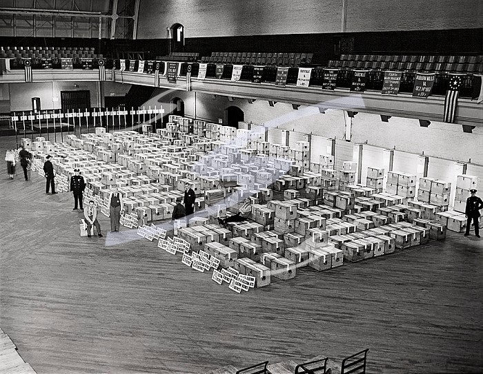 New York, New York, March 11, 1943 New York City police stand guard as hundreds of ballot boxes, sealed with tape, rest on the floor of the 69th armory to await counting. The ballots inside will determine the city’s new city council.. Ballots Guarded And Ready for Counting 