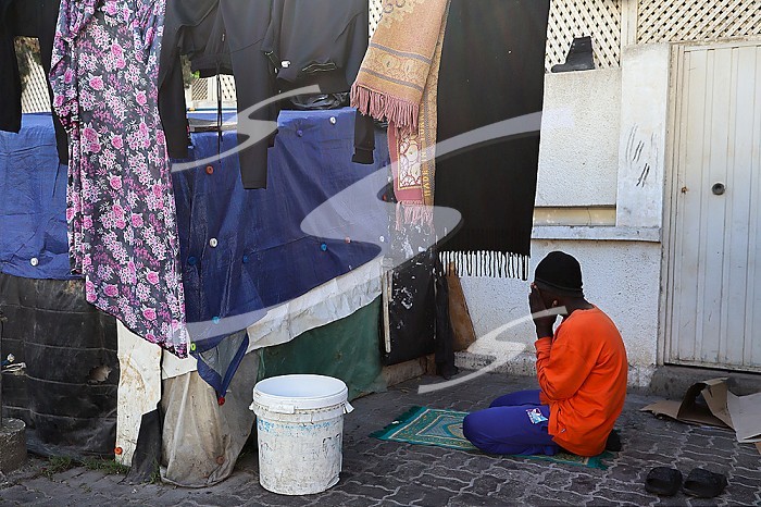 TUNIS, TUNISIA, An African migrant man praying at a street in Tunis. African migrants who arrived in Tunisia illegally take shelter at a street 200 meters from the International Organization for Migration (IOM) building in Tunis, Tunisia on March 18, 2024.. African migrant camp in Tunisia