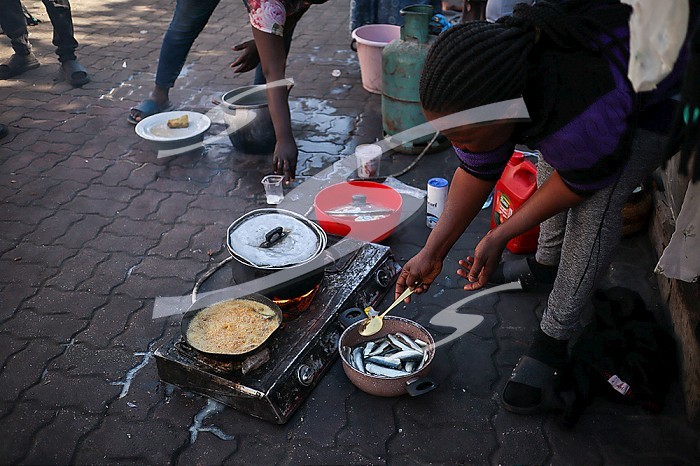 TUNIS, TUNISIA, An African migrant woman preparing a meal at a street in Tunis. African migrants who arrived in Tunisia illegally take shelter at a street 200 meters from the International Organization for Migration (IOM) building in Tunis, Tunisia on March 18, 2024.. African migrant camp in Tunisia