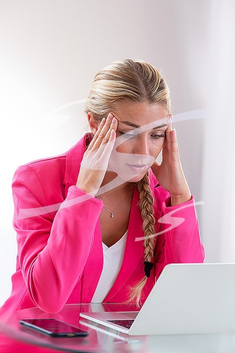 Woman facing her computer clutching her head with her fingers. their fingers.