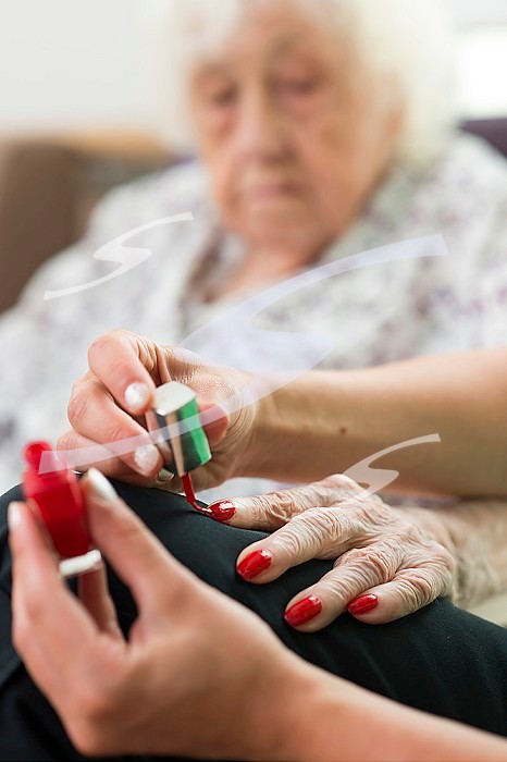 EHPAD - A nursing assistant applying nail polish on the hands of an elderly and deaf resident.
