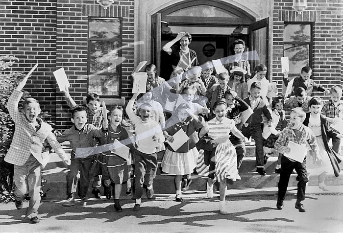 Mt. Carmel, Ohio:   c. 1963 Second graders rush out the door on the last day of school while their teacher bids them goodbye.